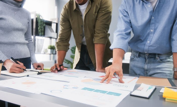 A business strategy meeting underway on a table using charts, graphs, and other documents.