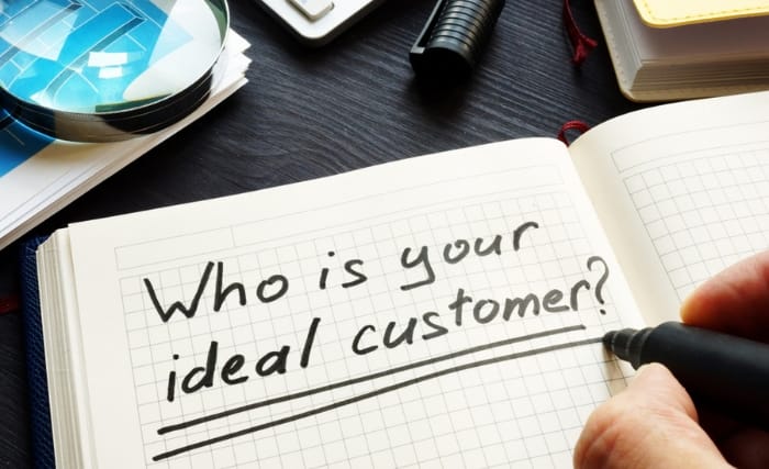 A pen writes 'who is your ideal customer?' in a notebook