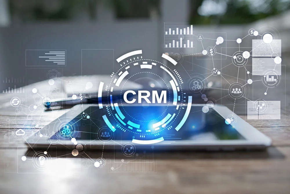 a tablet on a table, with an overlay of graphs, networks, and text saying 'CRM'