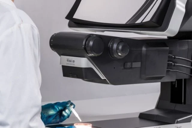 A scientist puts a sample in a petri dish with a 3D digital stereo microscope above it