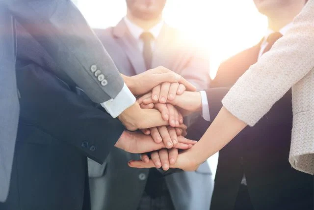 A corporate team put their hands together like Power Rangers