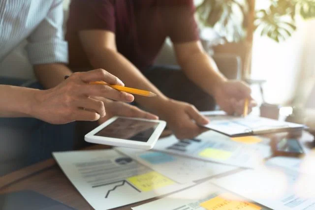 Two people devising a marketing strategy at a table using tablets and diagrams