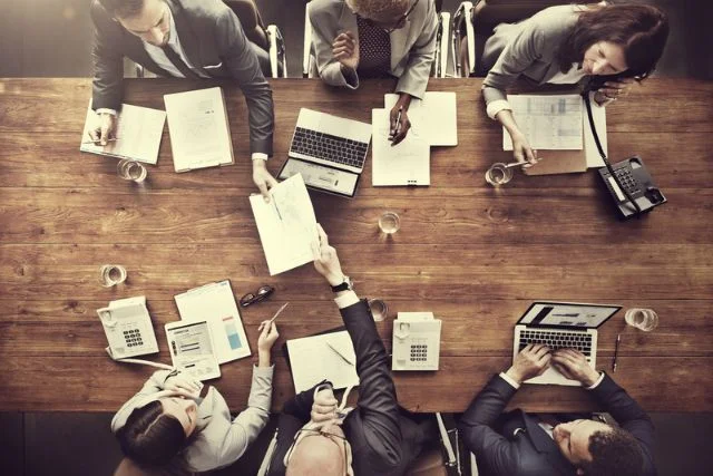 A marketing team sit around a wooden table discussing marketing strategy