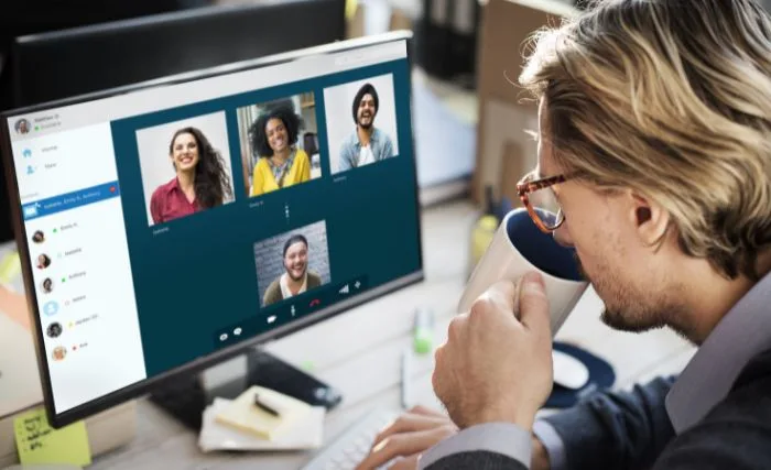 A man drinking coffee while having a hybrid work meeting
