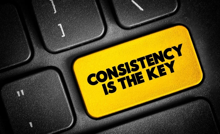 Close-up of a keyboard with a bright yellow key labelled “CONSISTENCY IS THE KEY” to emphasise reliable digital strategies.