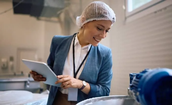 Food factory worker inspecting equipment with a tablet