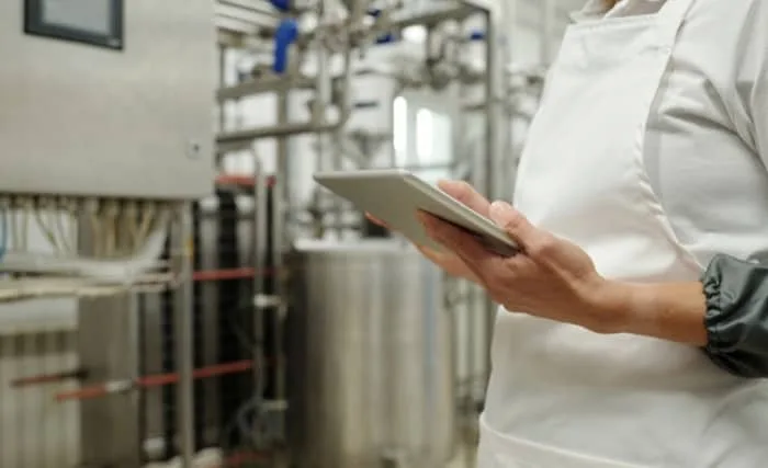 Close-up of food factory worker holding tablet near production equipment