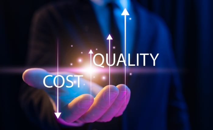 Cut costs without reducing quality, Hand holding a glowing graphic showing arrows rising next to the words cost and quality, representing the aim to cut costs without reducing quality.