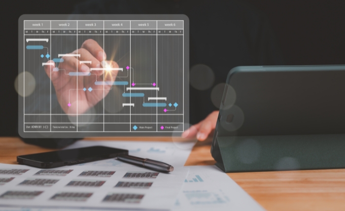 workforce allocation strategy: Hand interacting with digital project timeline and task planning interface on desk with tablet and documents, representing workforce allocation strategy and business planning.