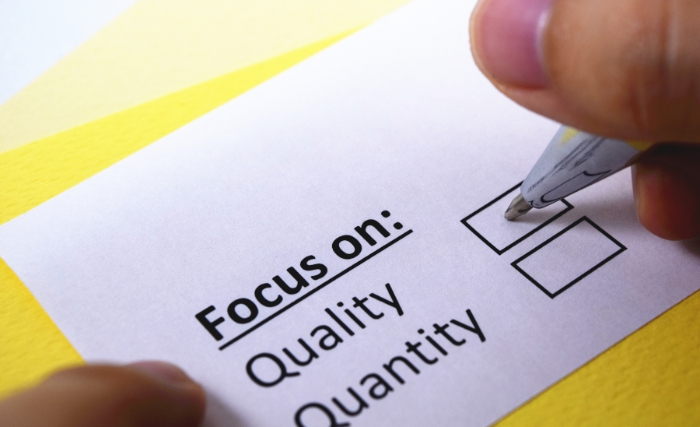 Lead quality vs lead quantity: A close-up of a hand ticking a checkbox on a card printed with "Focus on: Quality / Quantity", set against a yellow background.
