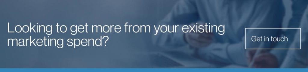 Looking to get more from your existing marketing spend: A wide banner with a dark blue overlay over a blurred image of a person writing, featuring white text reading "Looking to get more from your existing marketing spend?" and a outlined "Get in touch" button.